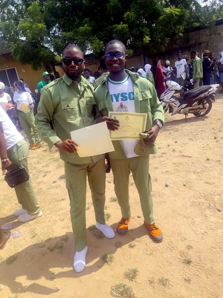 Rasheed Taiwo and a fellow corps member holding their Certificates of National Service at the Passing-Out Parade