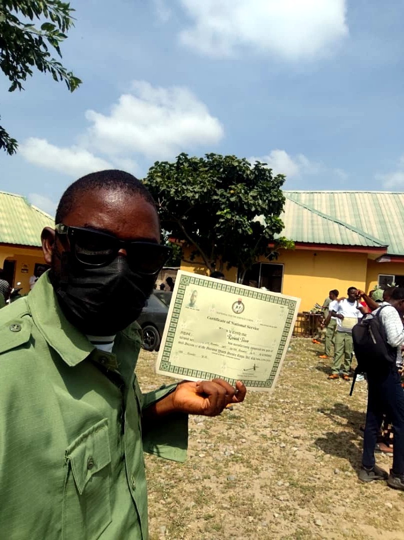 Rasheed Taiwo holding his NYSC Certificate of National Service on POP day