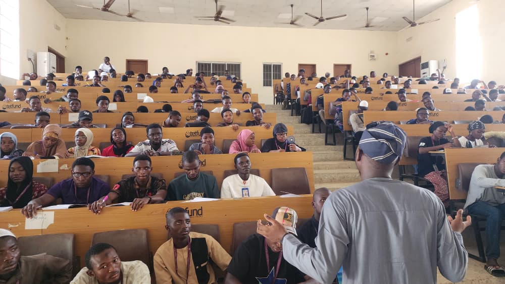 Rasheed teaching a large class of students in a lecture hall